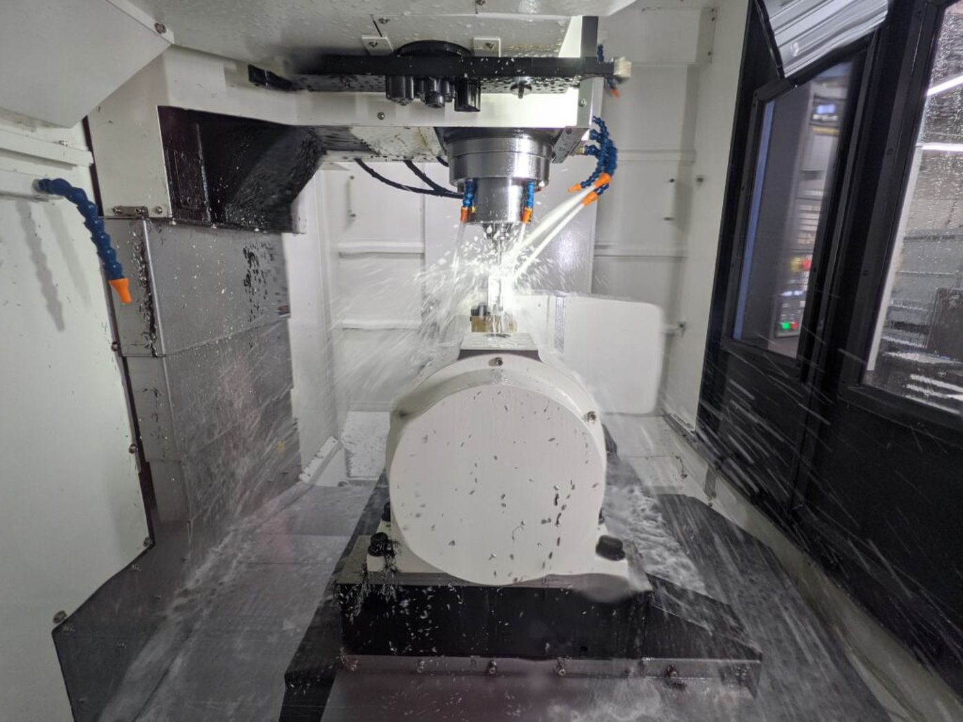 5-axis machining center cutting a part with coolant
